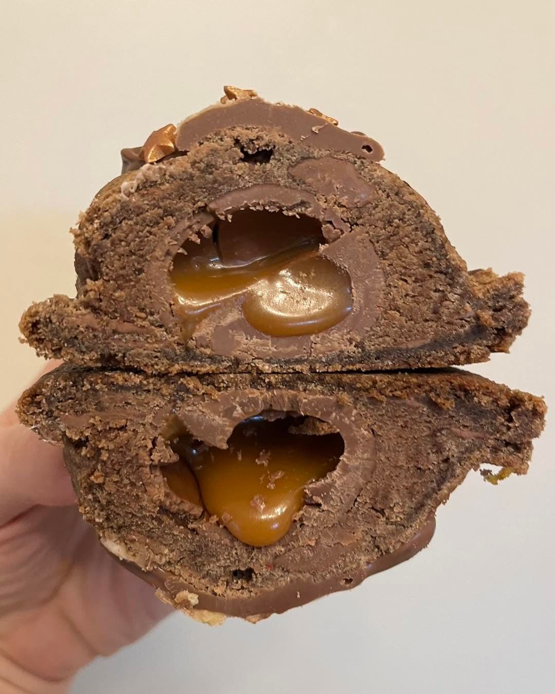 Caramel deluxe stuffed cookie cut open with a gooey centre