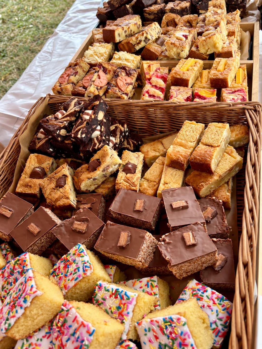 A bakery stall filled with brownies, blondies and sprinkle cake in wicker baskets
