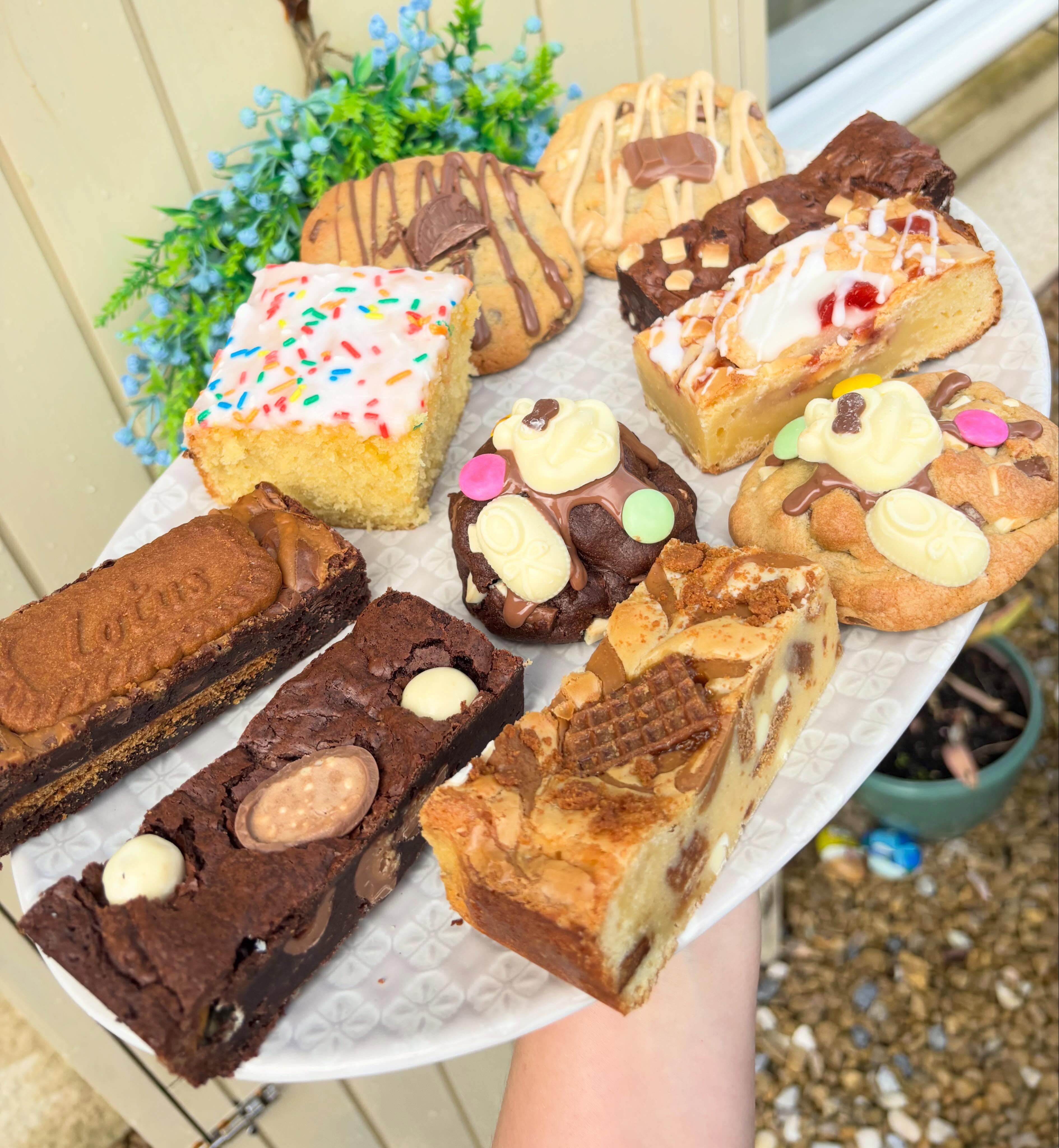 Mixed selection of brownies, blondies, cookies and cake slices on a white platter