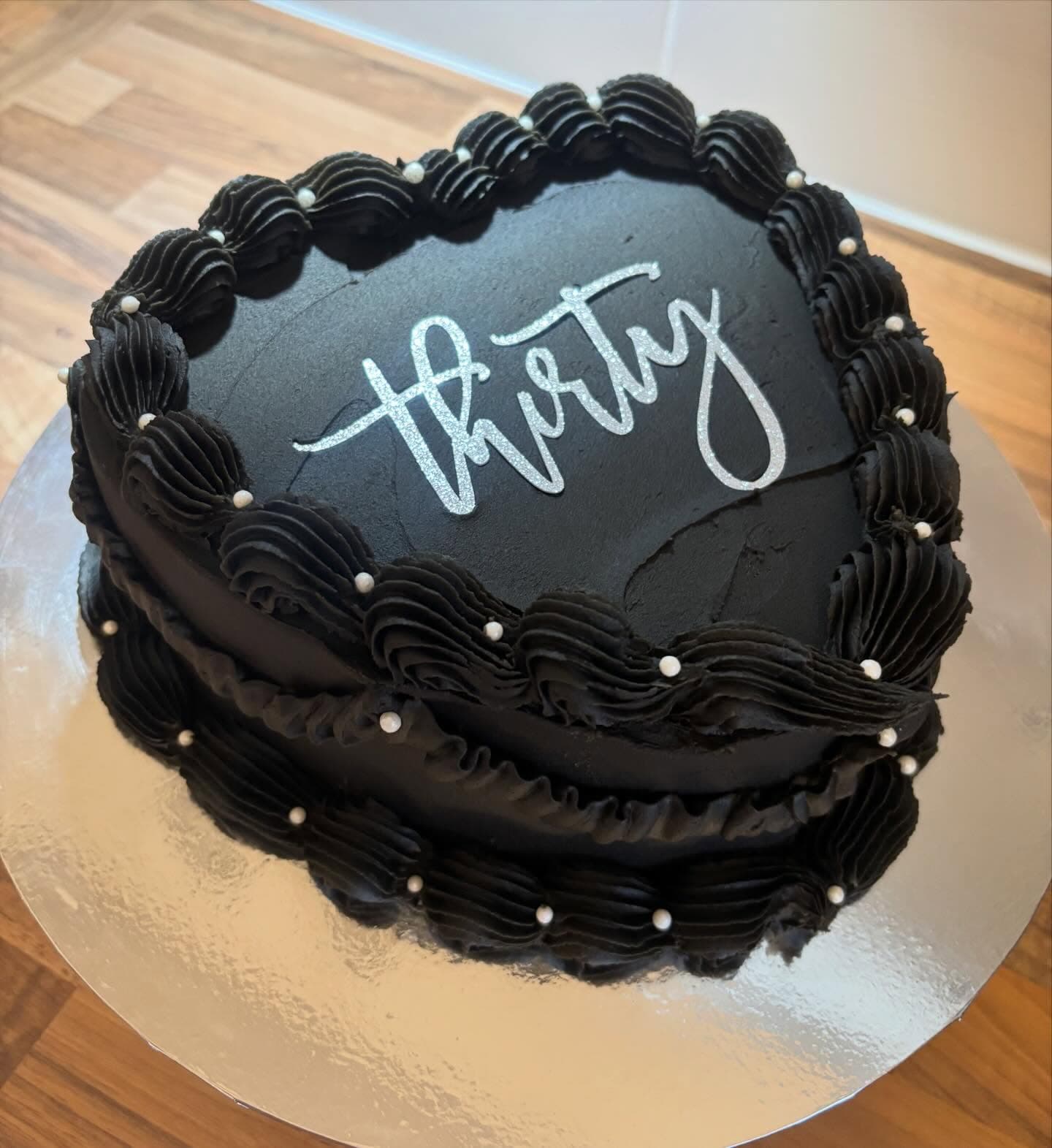 Black heart shaped cake with piped border and pearl details