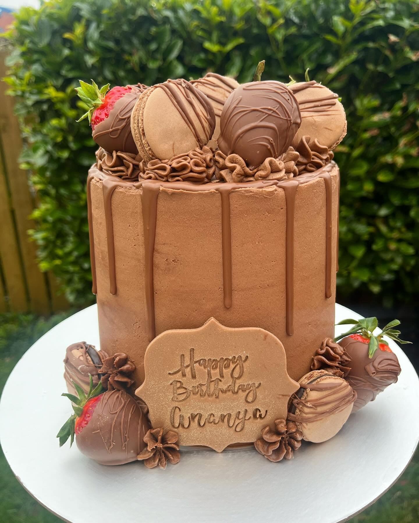 Chocolate celebration cake with macarons, strawberries and chocolate drip