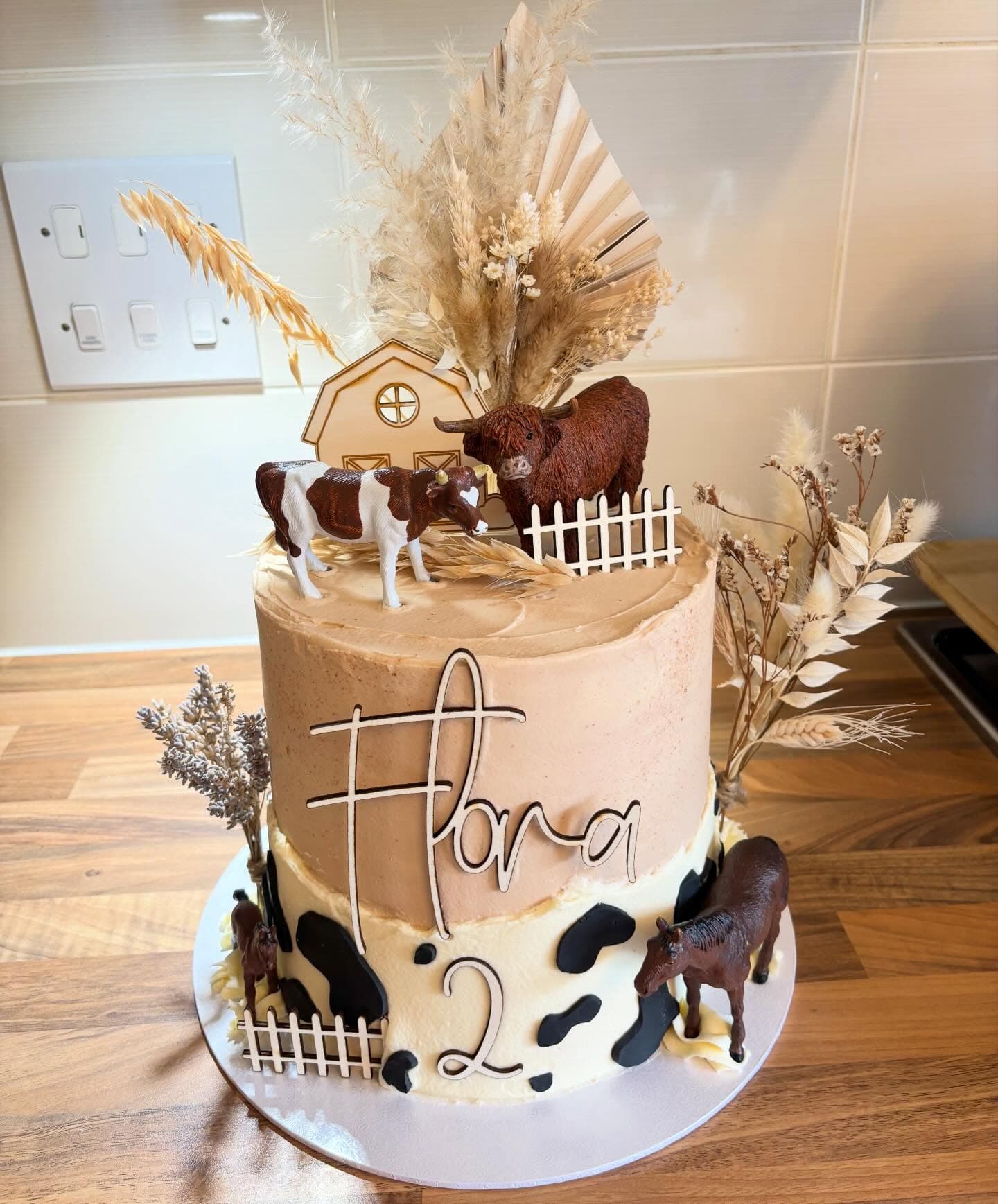 Two tier farm themed celebration cake with cow print and animal toppers