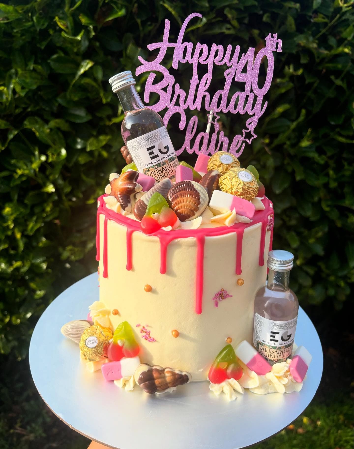 Cream cake with pink drip, sweets and miniature bottles