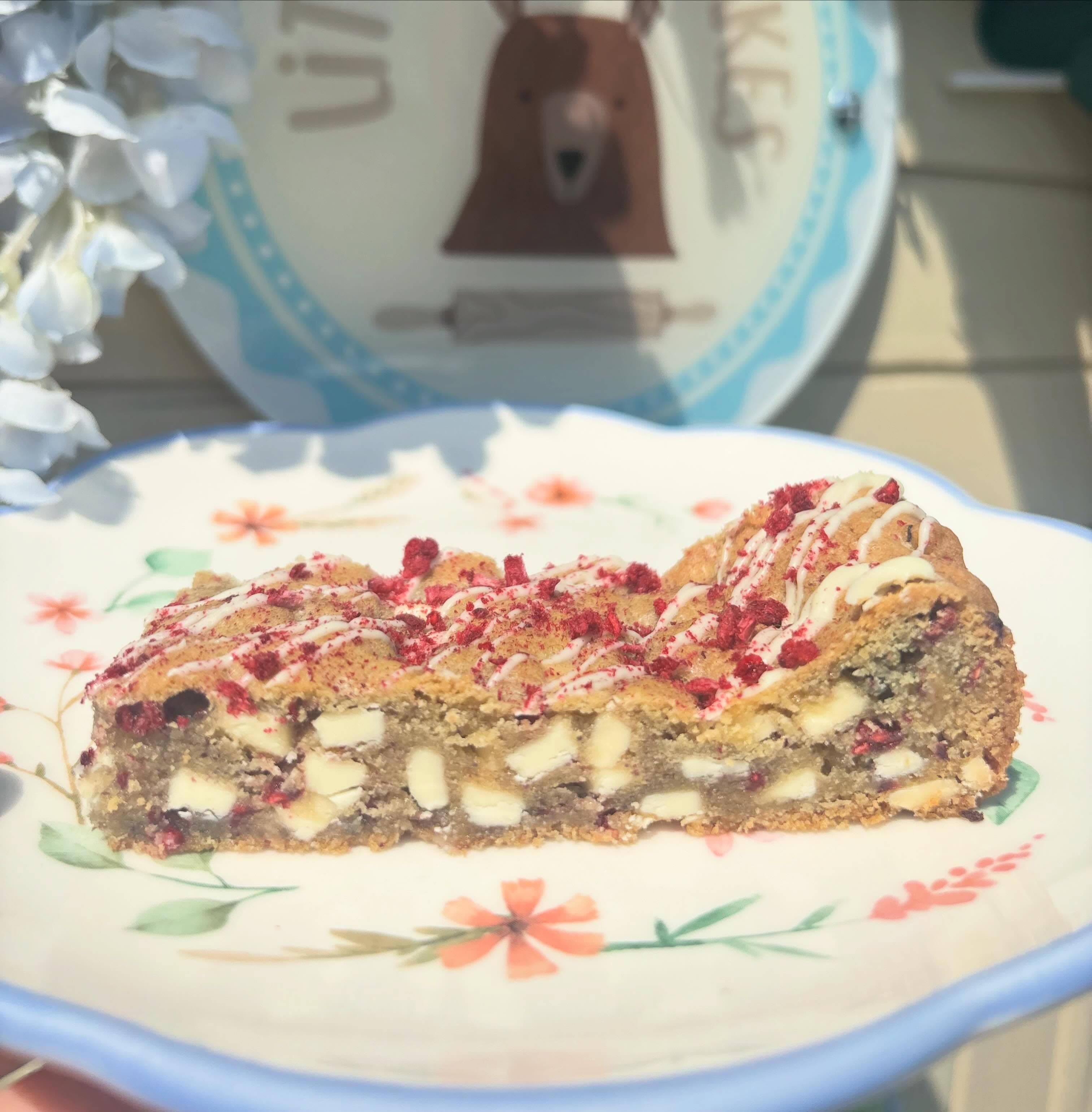 Raspberry and white chocolate cookie bar slice on a Little Bear Bakes plate