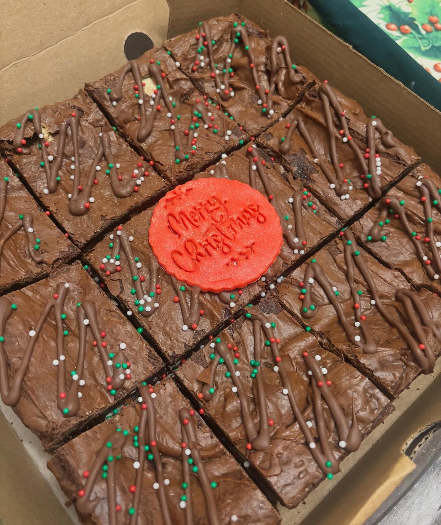 Tray of Christmas brownies with festive sprinkles and a Merry Christmas topper