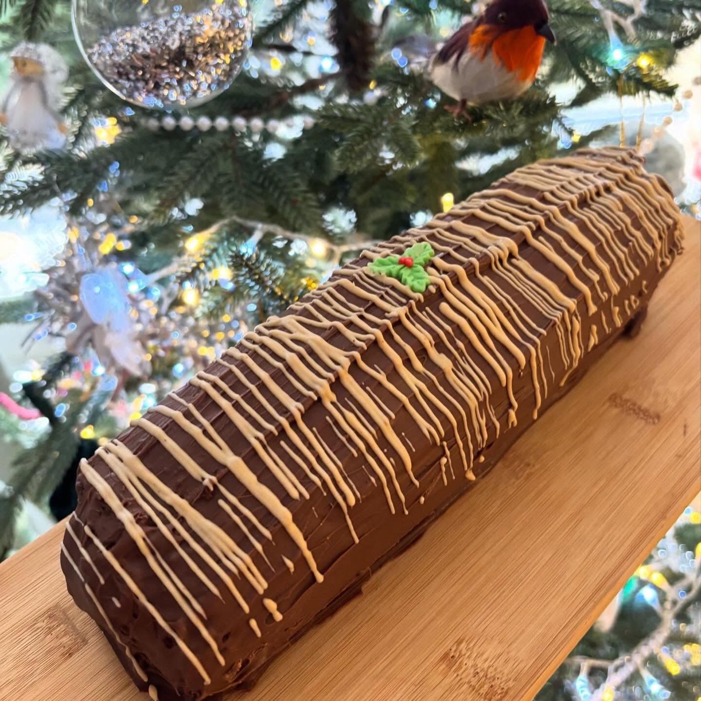 Christmas brownie yule log with chocolate drizzle on a wooden board