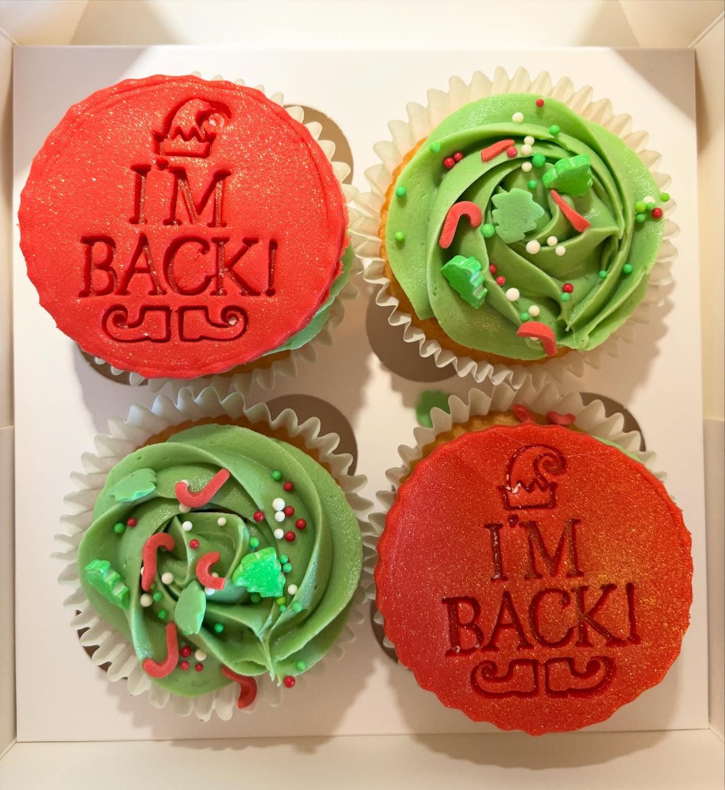 Box of Elf on the Shelf Christmas cupcakes with red and green toppings