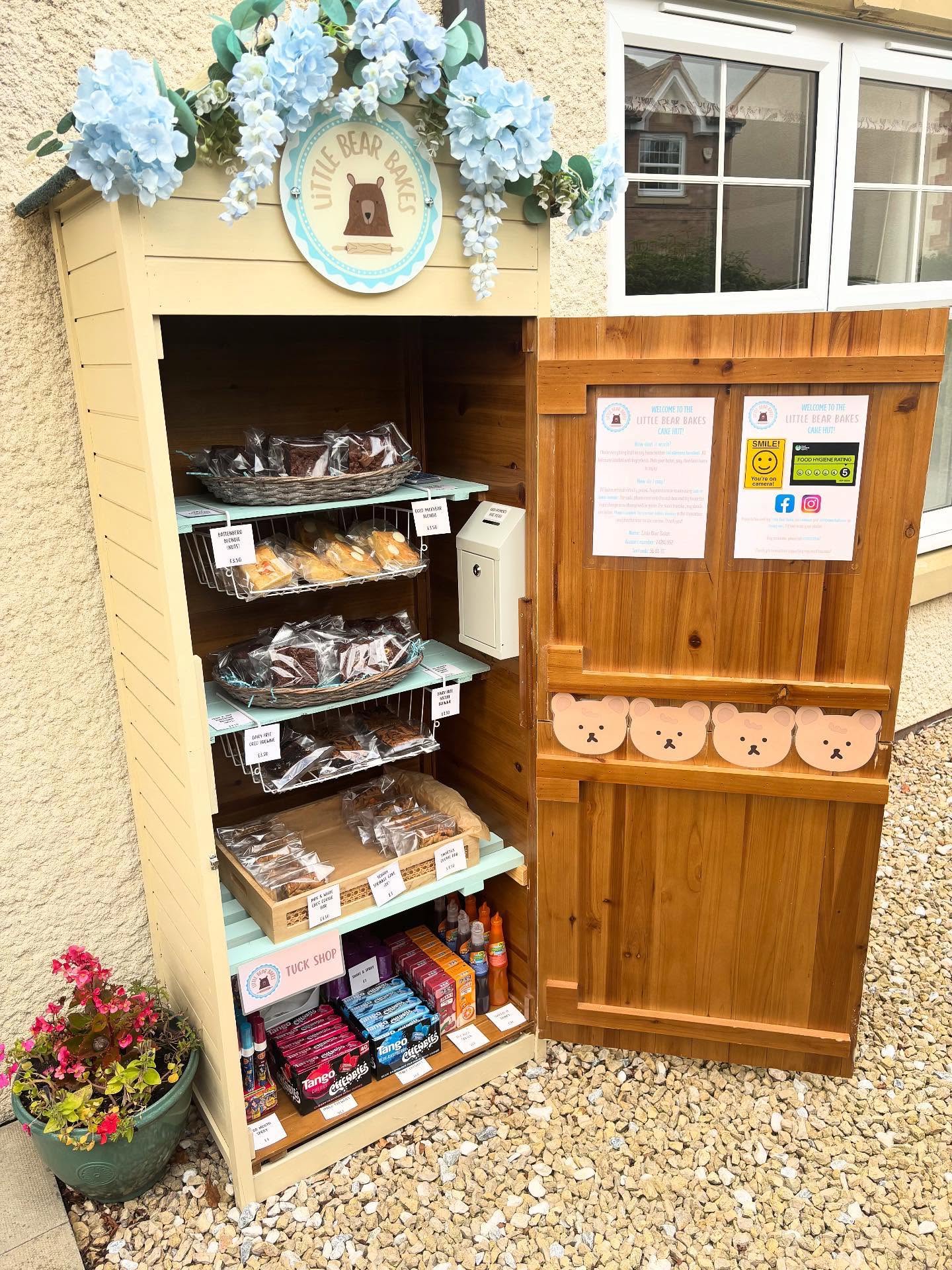 The Little Bear Bakes cake shed, decorated with blue flowers and stocked with homemade treats