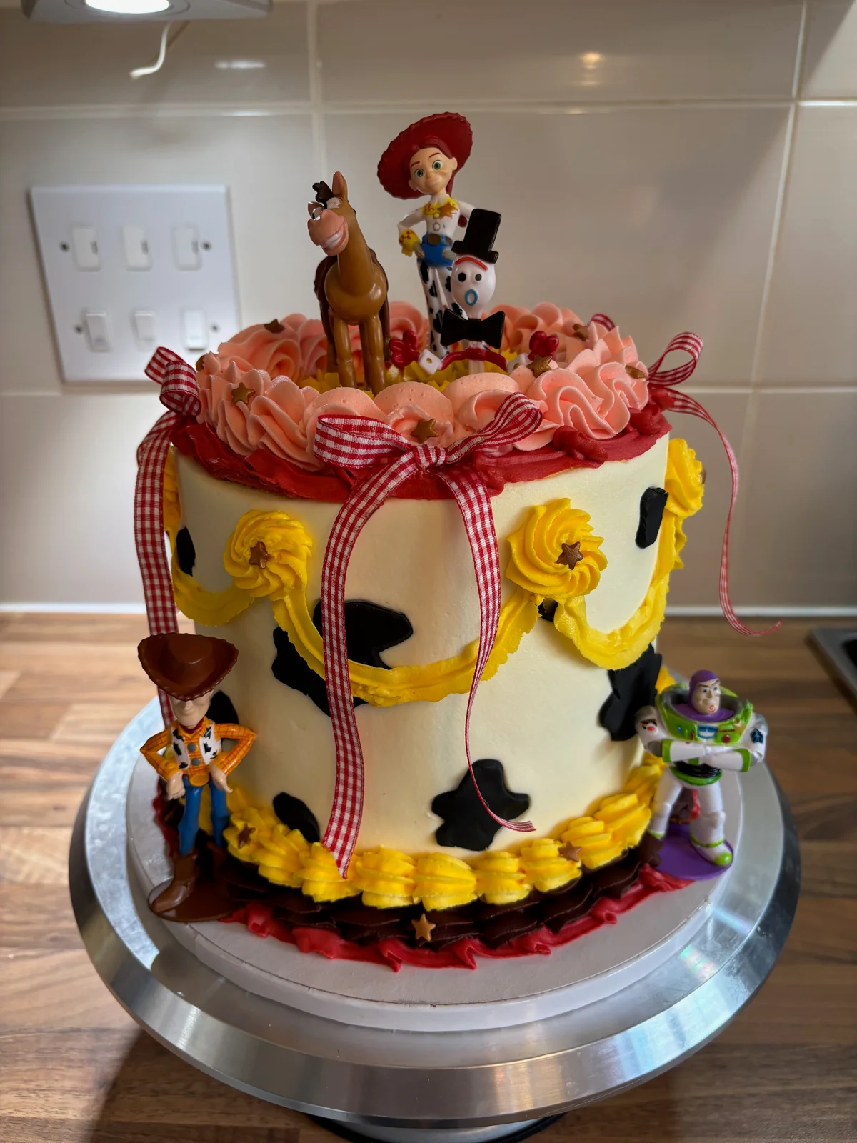 Toy Story birthday cake with cow print, colourful piping, gingham bows and character toppers